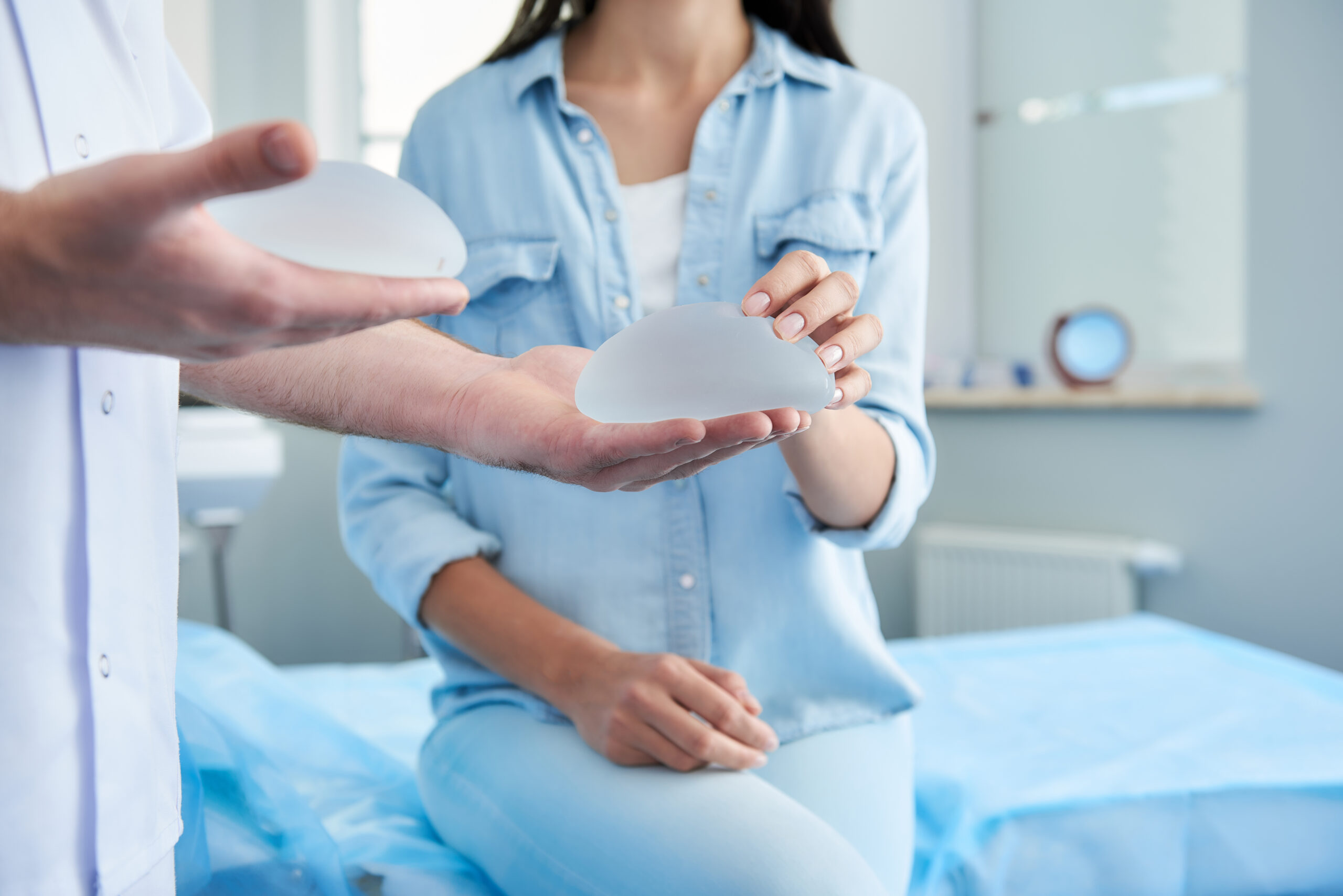 Woman touching breast implant during consultation with her plastic surgeon